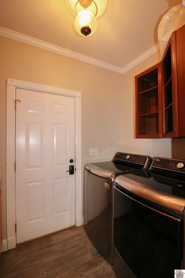 washroom featuring dark hardwood / wood-style floors, washing machine and dryer, ornamental molding, and a textured ceiling