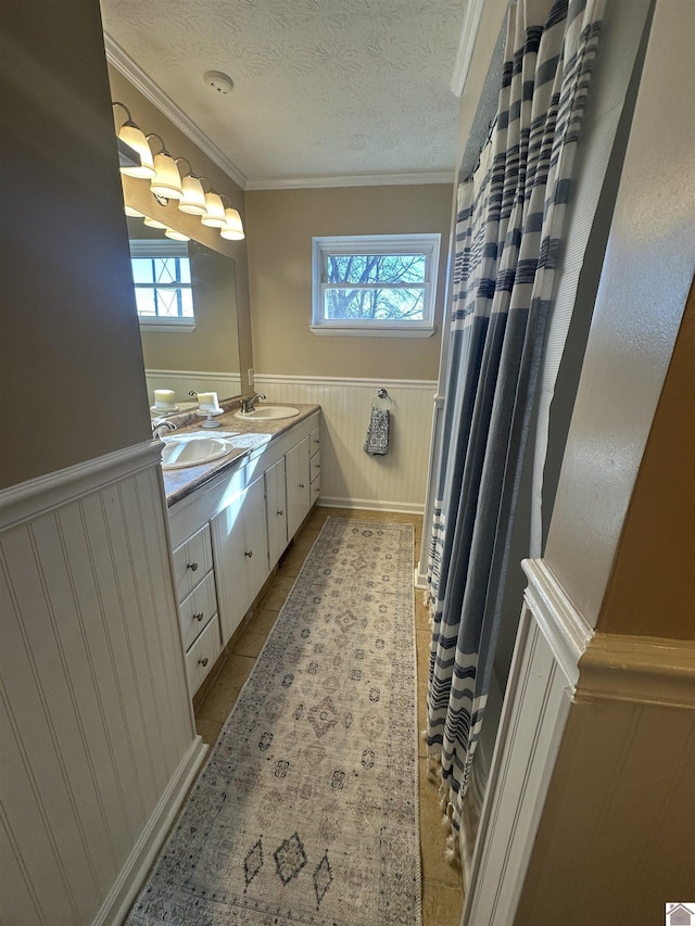 bathroom featuring tile patterned flooring, a textured ceiling, wooden walls, vanity, and ornamental molding