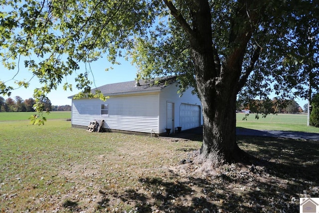 view of side of property with a lawn, a garage, and an outbuilding