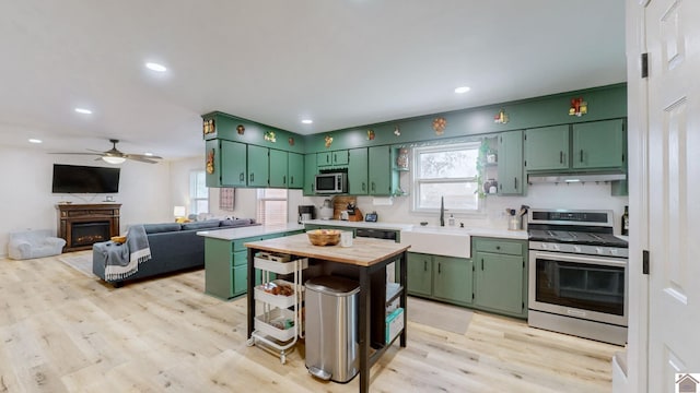 kitchen with sink, light wood-type flooring, green cabinetry, and appliances with stainless steel finishes