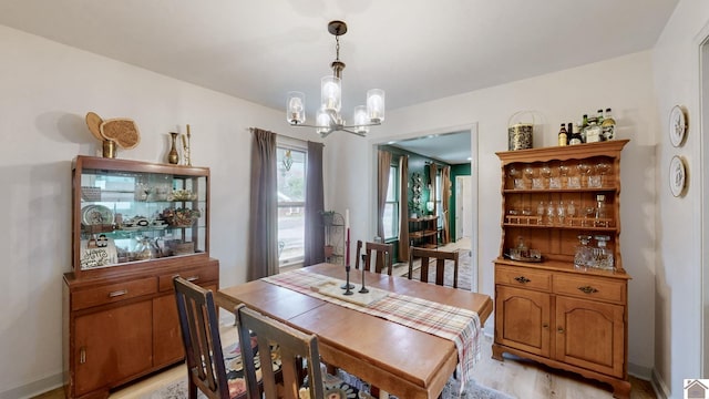 dining space with light hardwood / wood-style floors and an inviting chandelier