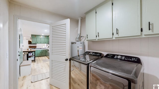 laundry area featuring washer and clothes dryer, cabinets, light wood-type flooring, and gas water heater