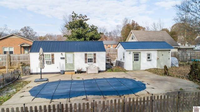 rear view of house with a patio area and a covered pool