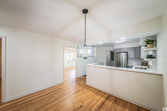 kitchen with kitchen peninsula, gray cabinetry, sink, light hardwood / wood-style flooring, and stainless steel refrigerator