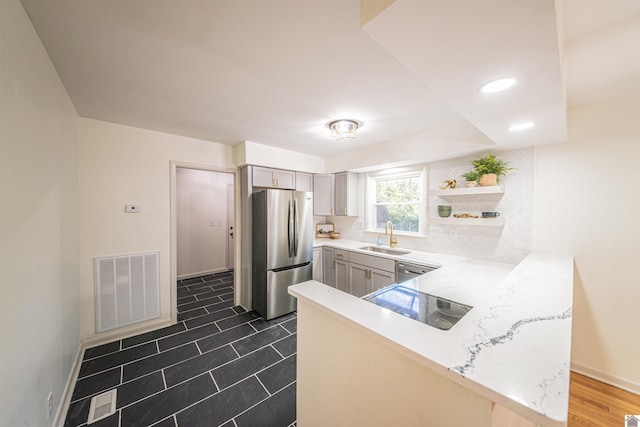 kitchen featuring kitchen peninsula, stainless steel appliances, gray cabinetry, and sink