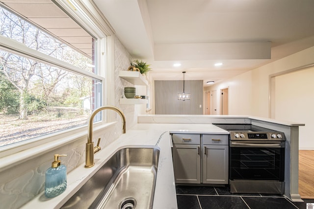 kitchen featuring gray cabinetry, electric range, kitchen peninsula, decorative light fixtures, and dark tile patterned flooring