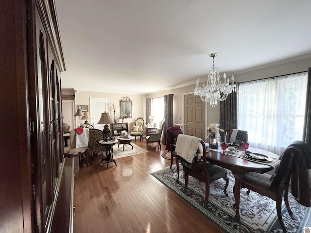 dining space with crown molding, wood-type flooring, and an inviting chandelier