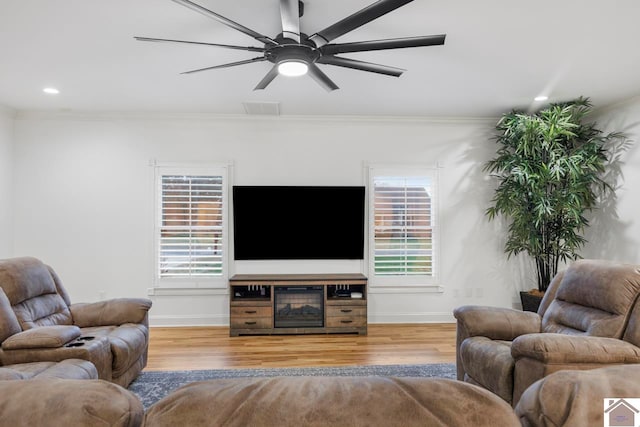 living room featuring hardwood / wood-style floors, crown molding, and a healthy amount of sunlight