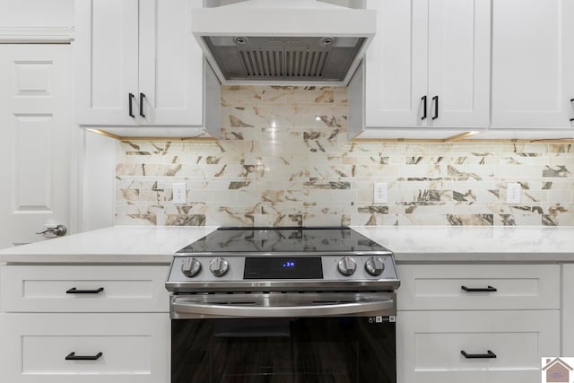 kitchen featuring white cabinets, stainless steel electric range oven, and wall chimney range hood