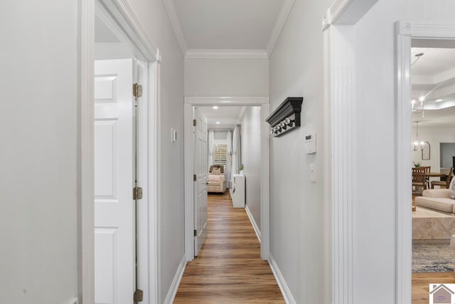 corridor with hardwood / wood-style flooring, a notable chandelier, and ornamental molding