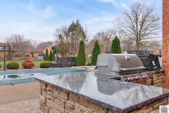 view of patio / terrace with a covered pool and a grill