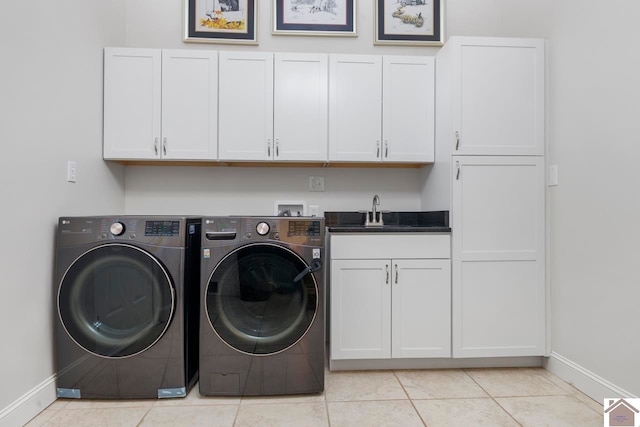 clothes washing area with washer and clothes dryer, sink, light tile patterned floors, and cabinets