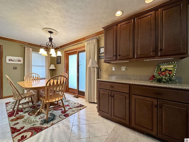 kitchen with light tile patterned floors, dark brown cabinetry, an inviting chandelier, and ornamental molding