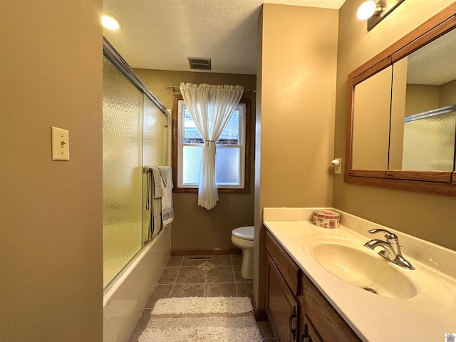 full bathroom featuring enclosed tub / shower combo, tile patterned floors, a textured ceiling, toilet, and vanity