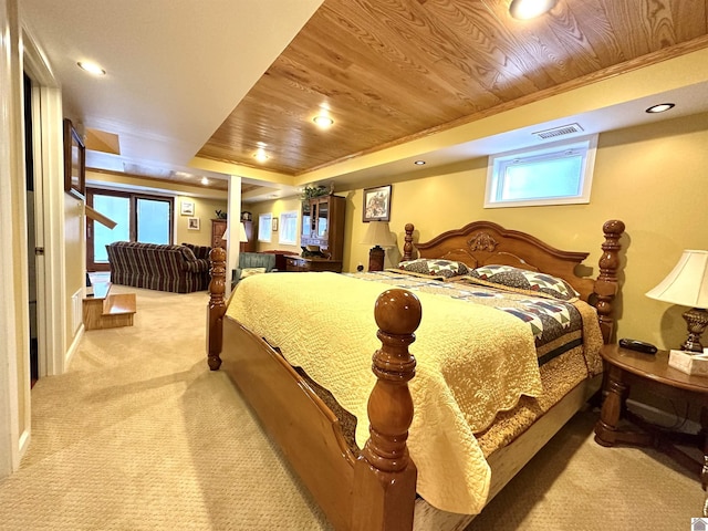 carpeted bedroom with wood ceiling, ornamental molding, and a tray ceiling