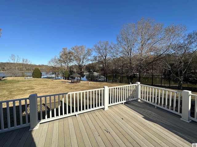 wooden terrace featuring a water view and a lawn