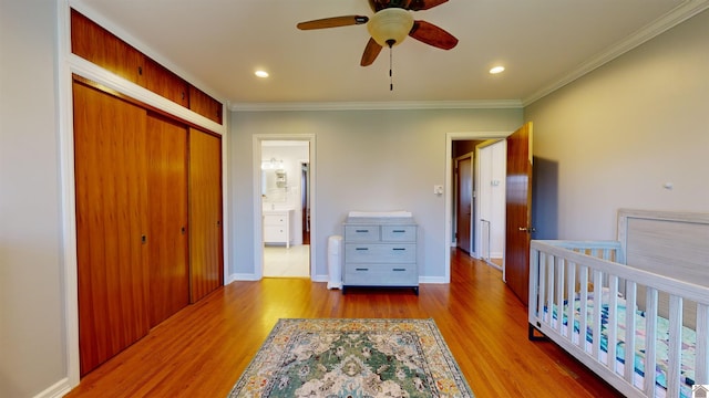 bedroom featuring connected bathroom, ceiling fan, crown molding, a closet, and hardwood / wood-style flooring