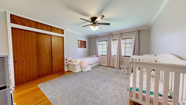 bedroom featuring ceiling fan, a closet, crown molding, and a crib