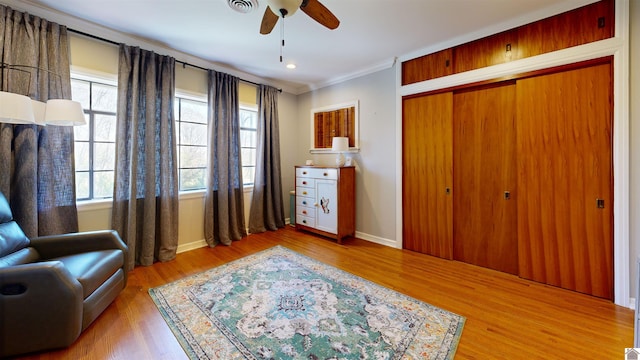 living area with wood-type flooring, ceiling fan, and crown molding