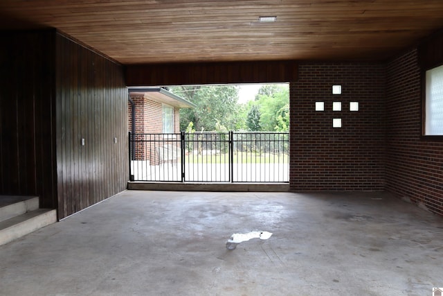 exterior space with wooden walls, concrete floors, wood ceiling, and brick wall