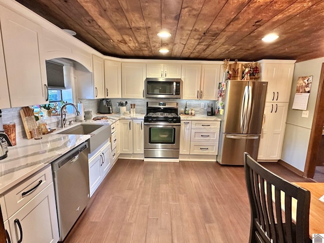 kitchen with sink, stainless steel appliances, light hardwood / wood-style floors, white cabinets, and wood ceiling