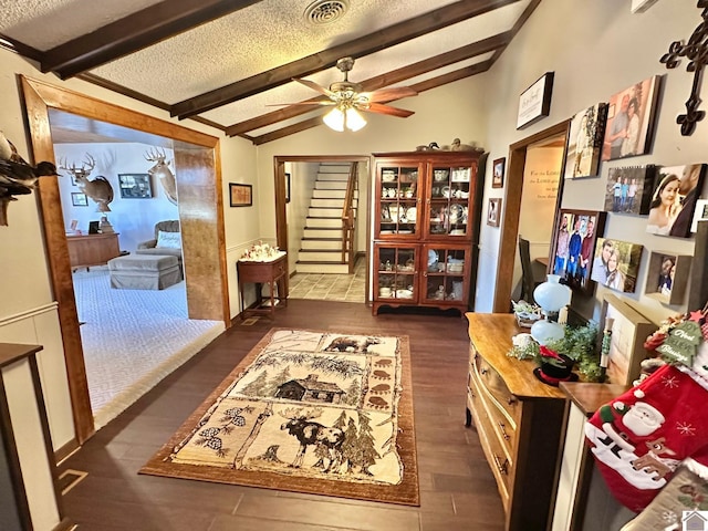 interior space with a textured ceiling, vaulted ceiling with beams, dark hardwood / wood-style floors, and ceiling fan