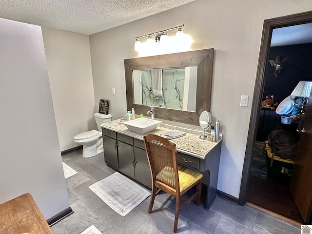 bathroom featuring vanity, a textured ceiling, and toilet