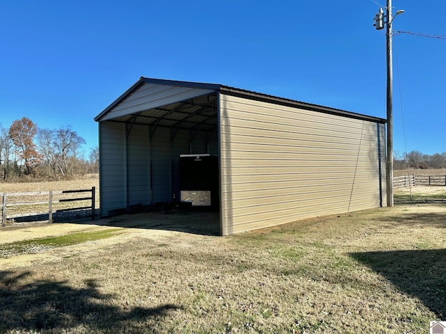 view of outbuilding featuring a rural view, a carport, and a lawn