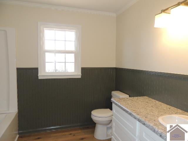 bathroom with ornamental molding, vanity, hardwood / wood-style floors, toilet, and a tub