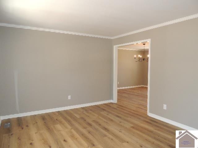 empty room with hardwood / wood-style flooring, an inviting chandelier, and crown molding