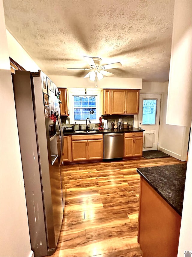 kitchen with a textured ceiling, sink, light wood-type flooring, and stainless steel appliances