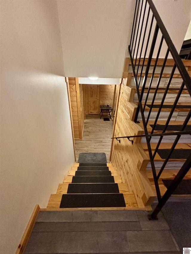 stairway featuring wood-type flooring and wooden walls