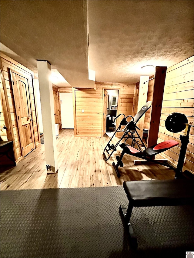 workout room with light hardwood / wood-style flooring and wooden walls