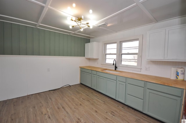 kitchen with sink, light hardwood / wood-style flooring, butcher block countertops, white cabinetry, and a chandelier