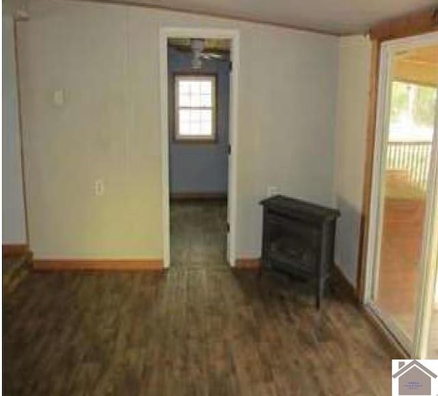 unfurnished room featuring a wood stove and dark wood-type flooring