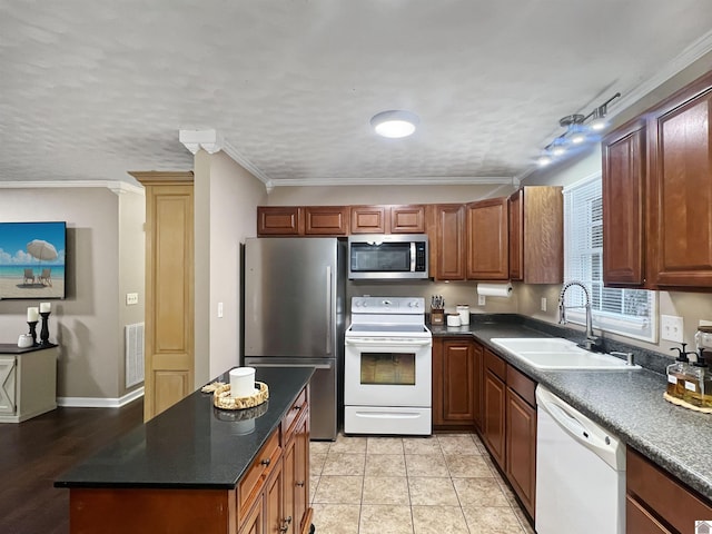 kitchen featuring track lighting, crown molding, sink, light tile patterned flooring, and stainless steel appliances