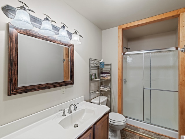 bathroom featuring tile patterned flooring, a shower with door, vanity, and toilet