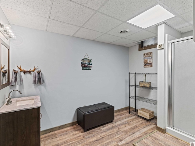 bathroom featuring hardwood / wood-style flooring, a drop ceiling, walk in shower, and vanity