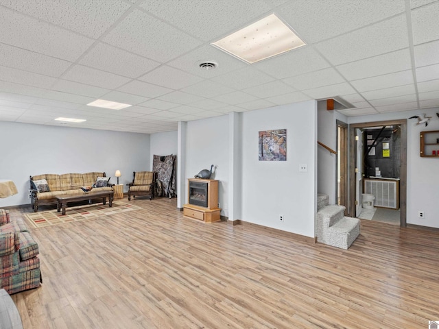 living room with light hardwood / wood-style flooring and a drop ceiling