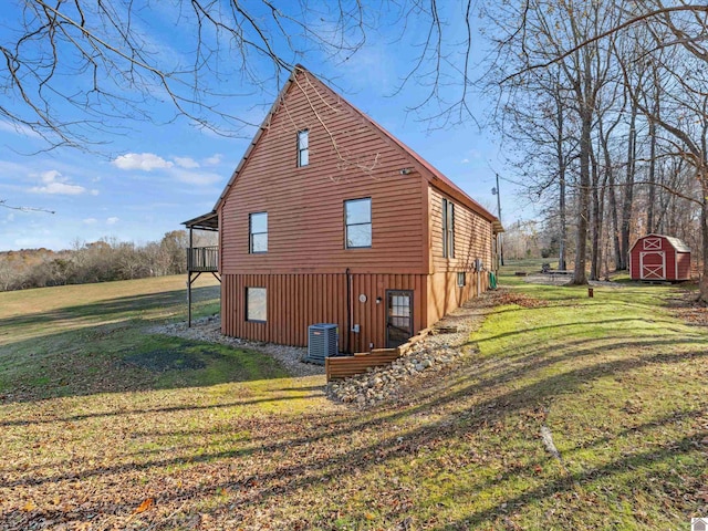 view of property exterior featuring a lawn, a wooden deck, cooling unit, and a shed