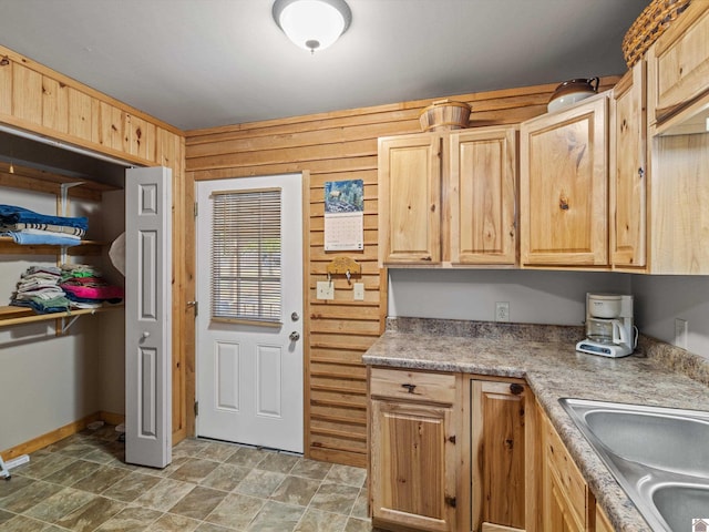 kitchen with wood walls, light brown cabinets, and sink