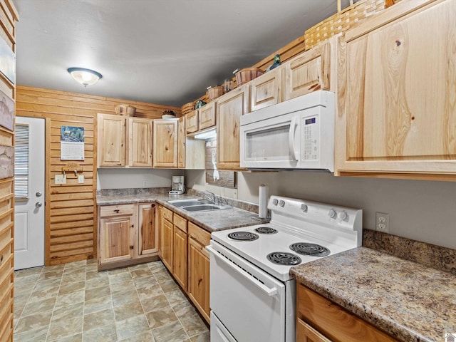 kitchen with light brown cabinets, white appliances, sink, wooden walls, and light stone countertops