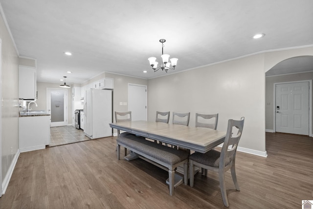 dining area with crown molding, light hardwood / wood-style flooring, a chandelier, and sink