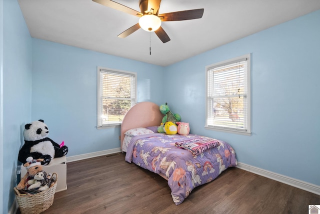 bedroom with ceiling fan, dark hardwood / wood-style flooring, and multiple windows