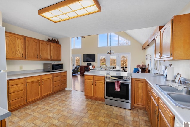 kitchen with sink, a textured ceiling, a notable chandelier, kitchen peninsula, and stainless steel appliances