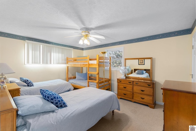 bedroom with ceiling fan, light colored carpet, and a textured ceiling