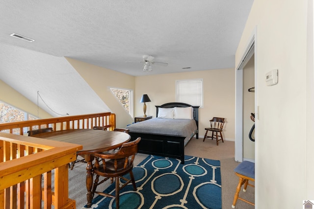 carpeted bedroom with ceiling fan and a textured ceiling