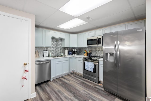 kitchen featuring decorative backsplash, appliances with stainless steel finishes, a paneled ceiling, sink, and dark hardwood / wood-style floors