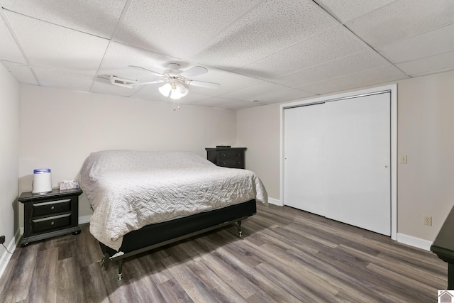 bedroom featuring a closet, a paneled ceiling, ceiling fan, and dark hardwood / wood-style flooring