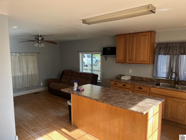 kitchen with ceiling fan, a center island, light wood-type flooring, and sink